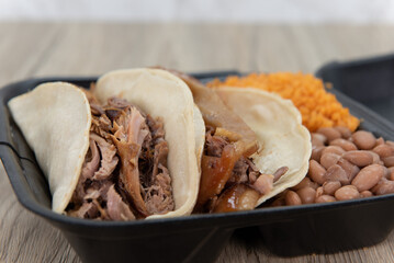 Mexican combination meal with two carnitas tacos loaded with meat and served with rice an beans