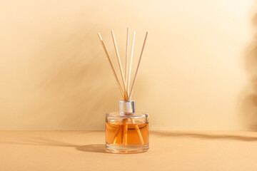 reed diffuser bottle on a beige background. Incense sticks for the home with a floral scent. The concept of eco-friendly fragrance for the home