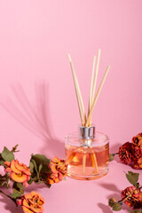 Obraz na płótnie Canvas reed diffuser with flowers. Incense sticks for the home with a floral scent with hard shadows. The concept of eco-friendly fragrance for the home