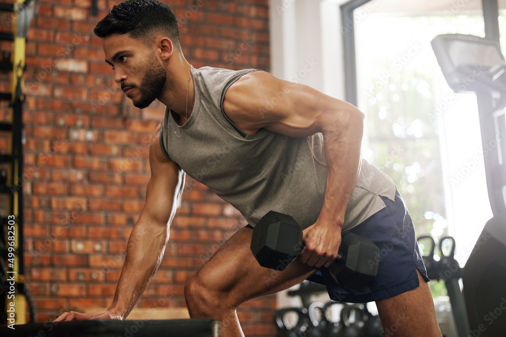 Poster no one works as hard as i do. shot of a young man working out with dumbbells in a gym.