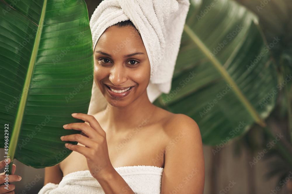 Wall mural Dont turn to toxic products when nature has all the solutions. Shot of a beautiful young woman wearing a towel around her head while posing behind a green leaf.