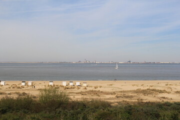 a dutch coast landscape in breskens with a sand beach with beach houses and dunes and flushing at the other side of the westerschelde sea