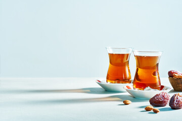 Traditional Turkish black tea in glass on saucer with dates on white background with copy space. Wide banner..