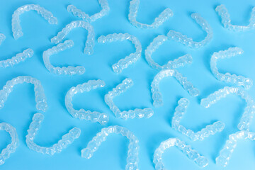 Invisible transparent orthodontic retainers invisalign on blue background. Aligner brackets or dental braces