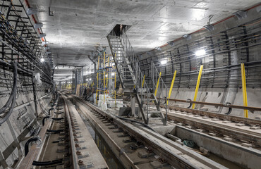 Construction of a new subway tunnel. Iron staircase in the middle of the tunnel leading to the technical room