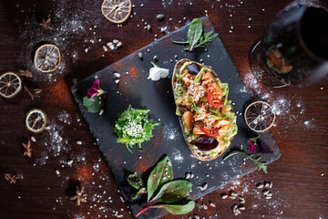 Fototapeta na wymiar wine glass and fresh sandwich with avocado, red salmon fried fish, seaweed