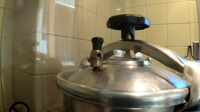 SLOW MOTION SHOT - Cooking in a pressure cooker. Valve of high pressure cooker steaming.