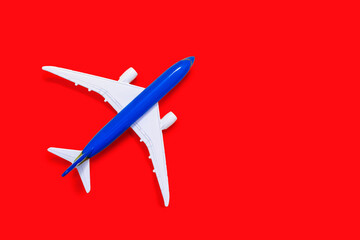 Aircraft model on a red background with free space for text or advertising. Tourism or freight transport concept. Toy airplane on a red background with a top view