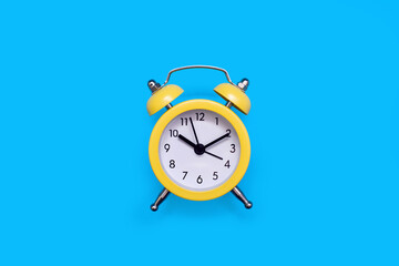 Yellow old-fashioned alarm clock with a dial on a blue background with free space for text. The concept of punctuality or routine. Vintage alarm clock from the past