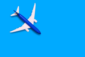 Fototapeta na wymiar Airplane model on a blue background with free space for text or advertising. Tourism or freight transport concept. Toy airplane on a blue background with a top view