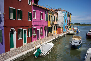 Fototapeta na wymiar Fishing motor boat and traditional colorful houses on the Burano island - one of attractive tourist objects in the Venetian lagoon
