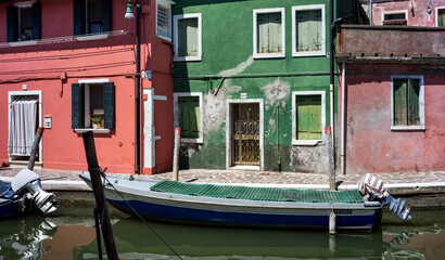 Fototapeta na wymiar Fishing motor boat and traditional colorful houses on the Burano island - one of attractive tourist objects in the Venetian lagoon
