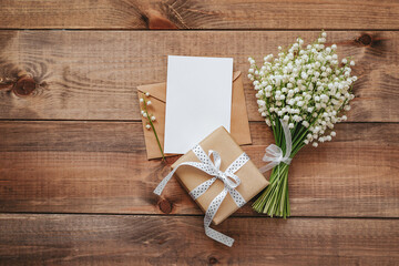 Lily of the valley and empty paper with text copy space on wooden background