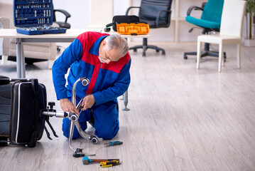 Old male repairman repairing office chair