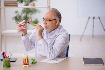 Old male dentist working in the clinic