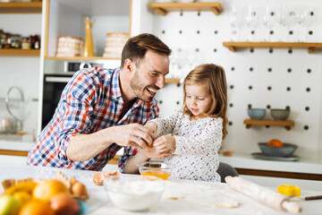 Cute girl and her father making cookies while baking in the kitchen
