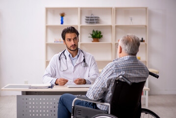 Obraz premium Old man in wheelchair visiting young male doctor