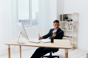manager in a suit glass of coffee sits at a tablein front of a computer Workspace