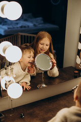 Brother and sister looking into mirror together