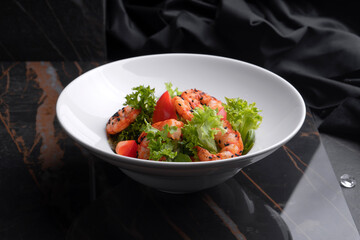 Shrimp salad on a black background and black cloth