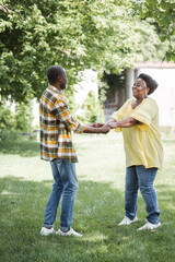 full length of senior african american couple smiling and dancing in park.