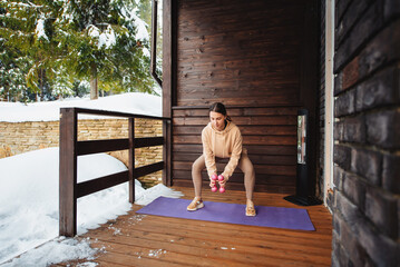 Woman training with dumbbells on terrace during winter time