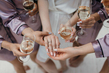 Bride and bridesmaids stand in silk robes with glasses of champagne