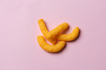 A few cheese doodles on pink background.