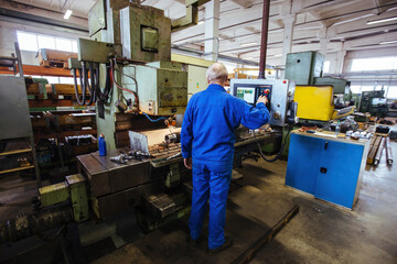 Factory engineer adjusting operation parameters of CNC lathe machine
