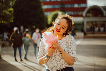 Mujer disfrutando de algodón de azúcar en sus vacaciones. Concepto de turismo. 