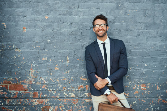 Urban business. Cropped portrait of a handsome young businessman standing against a grey facebrick wall.