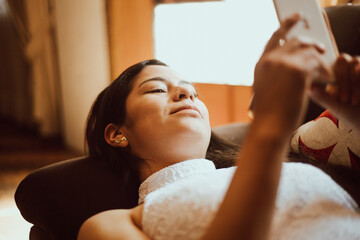 Obraz na płótnie Canvas Mujer revisa su teléfono mientras descansa. Concepto de tecnología y hogar.