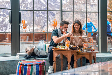 Couple enjoying food together while sitting against window in luxurious resort