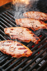 Rohe Lammrückensteaks gegrillt als close-up auf einem Holzkohlegrill mit Feuer