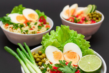 Beautiful Noodle Dish with Green Onions, Eggs, Green Pea, Red Hot Pepper, Greens and Lime on Sushi Mat. Instant Noodles with Vegetables