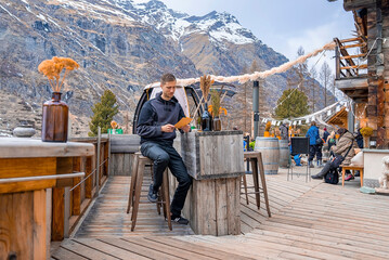 Man reading menu card while sitting at outdoor restaurant against mountain