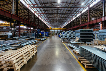 Metalworking factory production line. Rolls of steel and metal profiled parts in workshop - obrazy, fototapety, plakaty