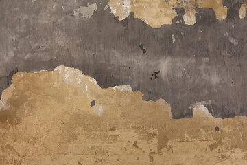 A weathered old wall with grunge texture. Concrete surface with peeling paint, abstract background.
