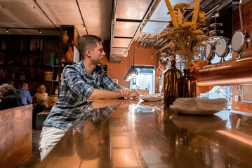 Young tourist sitting at bar counter in restaurant at luxurious ski resort