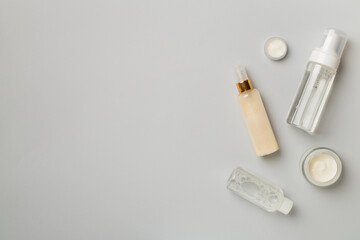 Different cosmetic bottles on color background, top view
