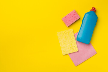 Bottle with dishwashing detergent and sponges on color background, top view