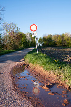 Path in the countryside, warning sign for cars, no enty, puddle after the rain, landscape in Germany