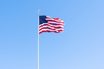 Beautiful American flag waving in the wind, with vibrant red white and blue colors against blue sky