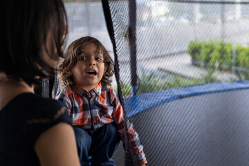 Mom and her Latin American son having fun on a trampoline at a children's playground. Mother's day...