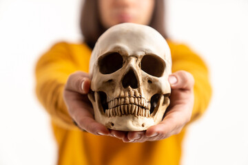 Young dark-haired man showing fake skull to the camera white background studio shot . High quality photo