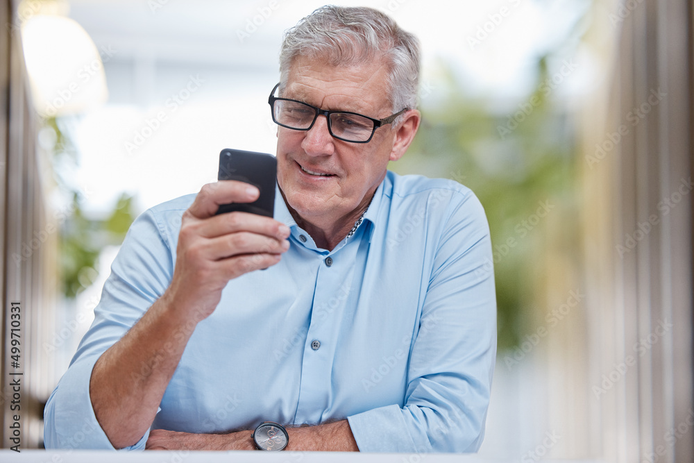 Poster checking my schedule from any device. shot of a mature businessman sitting alone in the office and u