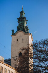 Obraz premium Tower of the Latin Cathedral of the Assumption of the Blessed Virgin in Lviv with a tree in the foreground. The historical part of the city, view from below against the blue sky.
