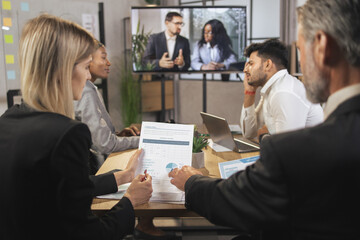 Business concept. Close up cropped shot of experienced multiethnic businesspeople, analyzing financial report with charts and diagramms during joint meeting in modern conference room.