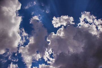 thick cumulus clouds, backlit, with very light edges, floating under a blue sky.