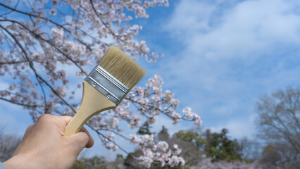 ハケを持つ手と桜｜建設業・塗装業　入社イメージ